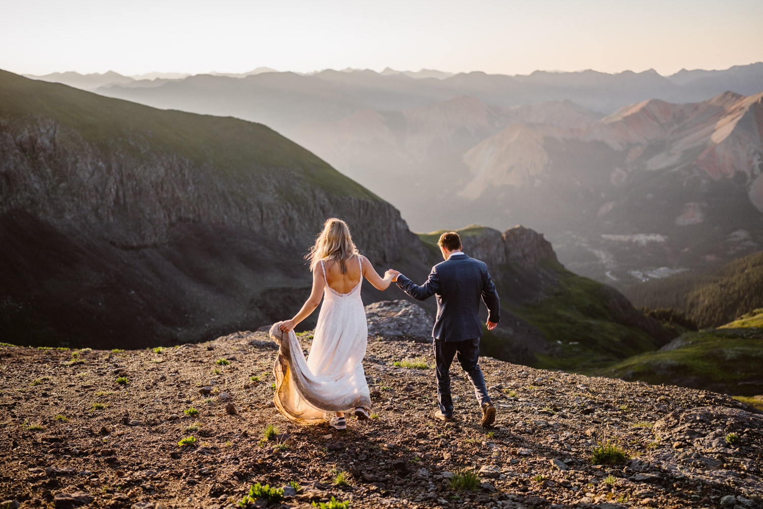 A couple hiking down a mountain in Colorado at sunrise.